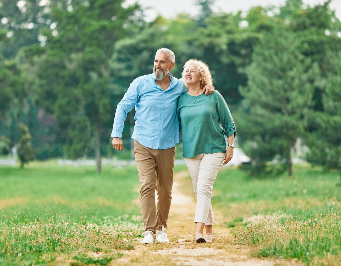Dos personas adultas paseando juntas por un camino del parque